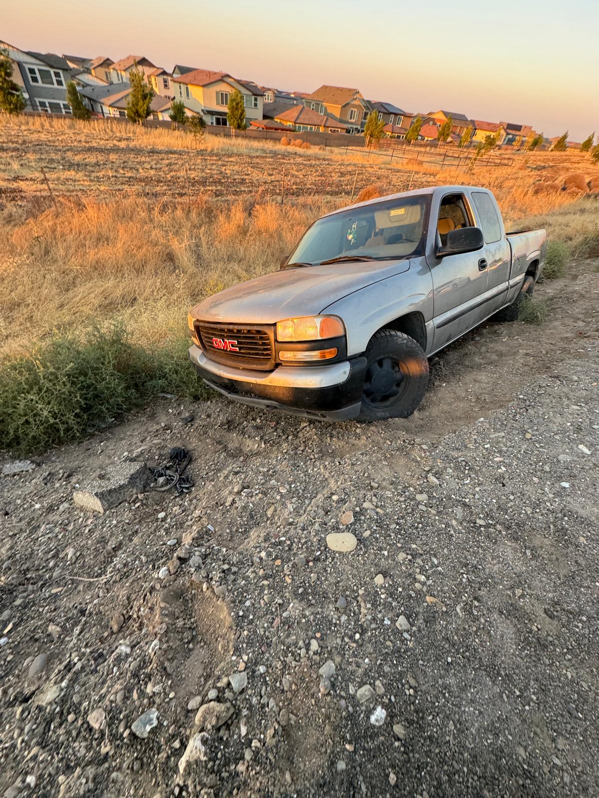 GMC pickup stuck off-road in soft dirt at sunset — ready for Rite Away Tow winch-out recovery